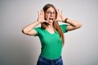 © Krakenimages.com - Young beautiful redhead woman wearing casual green t-shirt and glasses over white background Smiling cheerful playing peek a boo with hands showing face. Surprised and exited
