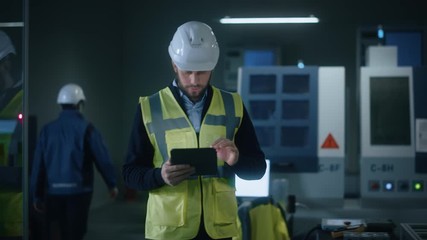 Aufkleber - Professional Engineer Wearing Safety Vest and Hardhat Walks Through Modern Factory Workshop, Uses Digital Tablet Computer. Handsome Professional Working in Industrial Facility with High Tech Machinery
