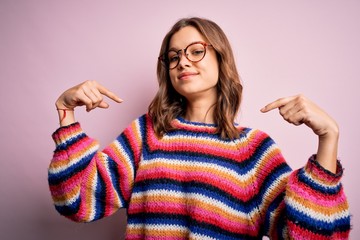 Young beautiful blonde girl wearing glasses and casual sweater over pink isolated background looking confident with smile on face, pointing oneself with fingers proud and happy.