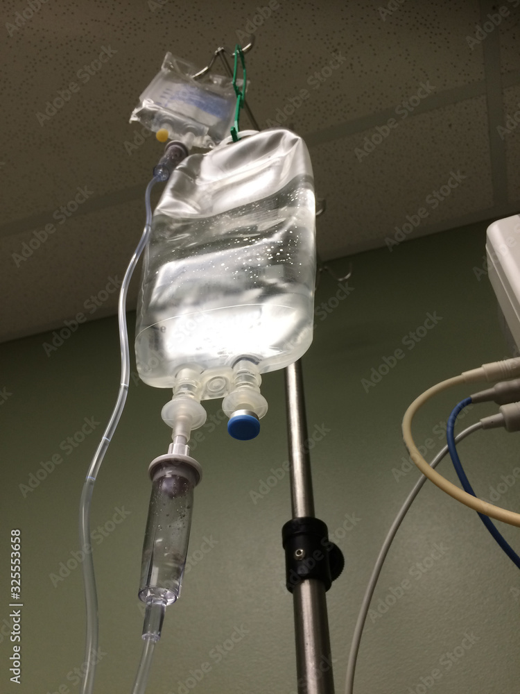 Bag of intravenous (IV) fluid drips / infuses saline and other injected drugs into patient in hospital room, emergency treatment or therapeutic patient care  