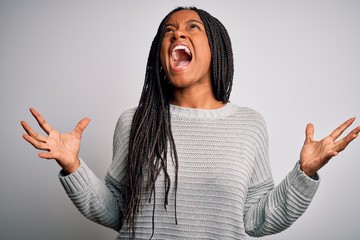 Young african american woman standing casual and cool over grey isolated background crazy and mad shouting and yelling with aggressive expression and arms raised. Frustration concept.