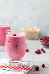 Wall Mural - Two glasses with freshly homemade smoothie of yogurt, oatmeal and cranberries on a gray table. Healthy eating concept. Vertical image with copyspace