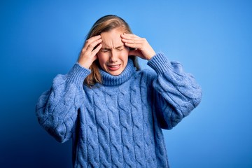 Sticker - Young beautiful blonde woman wearing casual turtleneck sweater over blue background with hand on headache because stress. Suffering migraine.