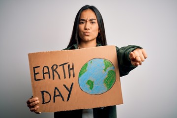 Canvas Print - Young beautiful asian woman holding banner asking for earth and enviroment conservation pointing with finger to the camera and to you, hand sign, positive and confident gesture from the front