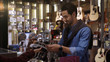 © Kittiphat - An upwardly mobile Middle Eastern man using a mobile phone - smartwatch to purchase product at the point of sale terminal in a retail store with nfc identification payment for verification