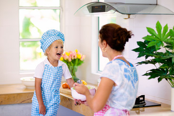 Wall Mural - Mother and child cook. Mom and kid cook in kitchen