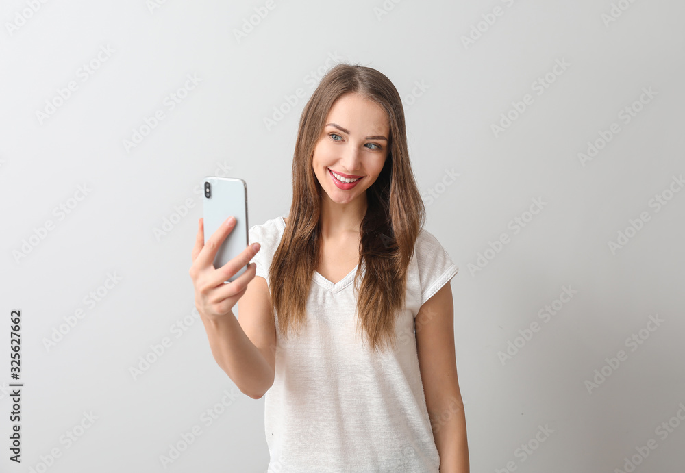 Young woman with mobile phone on light background