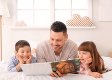 Father And His Little Children Reading Bedtime Story At Home
