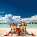 Fototapeta Londyn - Couple in loungers on beach at Maldives