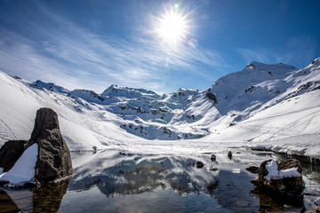 Wall Mural - Saint-Martin-de-Belleville, France - February 21, 2020: The snow-covered mountain and its reflection in Lac du Lou near Val Thorens resort