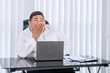 © Creativa Images - Fat Asian businessman feeling drowsy while working