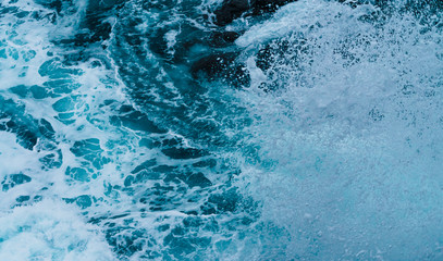 White sea foam produced when the waves collide with the rocks of the coast