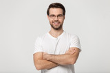 Fototapeta Do przedpokoju - Happy millennial confident man in glasses standing with folded hands.