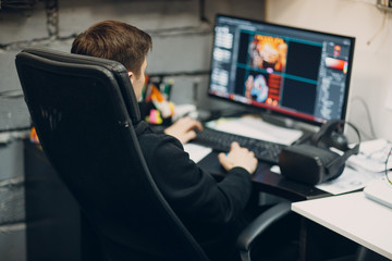 Wall Mural - Young man sitting on chair with computer desktop near virtual reality goggles, vr glasses headset