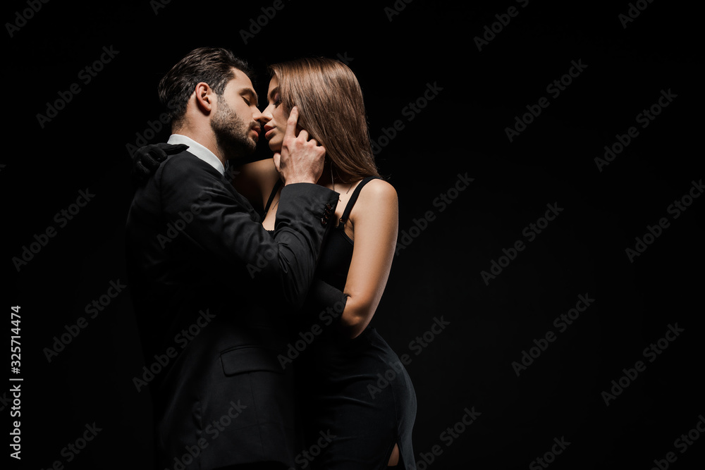 side view of handsome man touching face of attractive woman in dress isolated on black - obrazy, fototapety, plakaty 