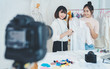 © sutthinon602 - Beautiful asian woman blogger showing clothes in front of camera to recording vlog video live streaming at her shop. Business online influencer on social media concept. Online Selling. Online Shopping