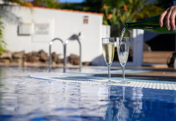 Pool party with two glasses with  bubbles white champagne or cava wine, romantic event or all inclusive holidays