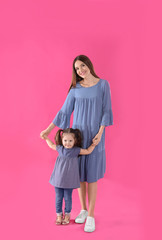 Poster - Young mother and little daughter on pink background