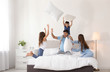 © New Africa - Happy family having pillow fight in bedroom