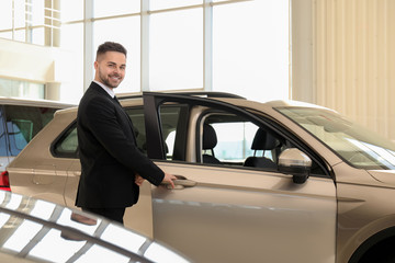 Wall Mural - Young salesman near new car in dealership