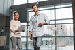 © LIGHTFIELD STUDIOS - pregnant asian businesswoman holding papers while standing near handsome colleague