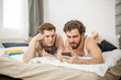 young caucasian gays lie on bed with smartphone in hands. homosexual happy male couple, young members of lgbt have their own family, spend morning together on bed