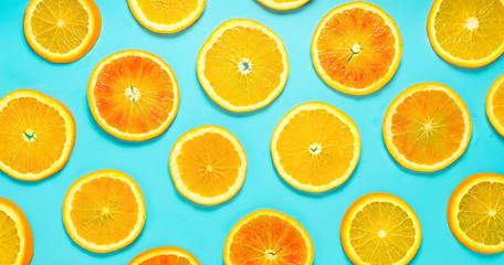 Wall Mural - Fruit pattern of orange slices on turquoise background. Top view.