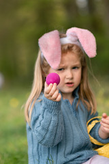 Wall Mural - Girl with bunny ears collects chocolate eggs for Easter