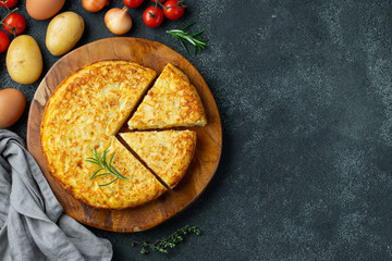 Spanish omelette with potatoes and onion, typical Spanish cuisine on a black concrete background. Tortilla espanola. Top view with copy space