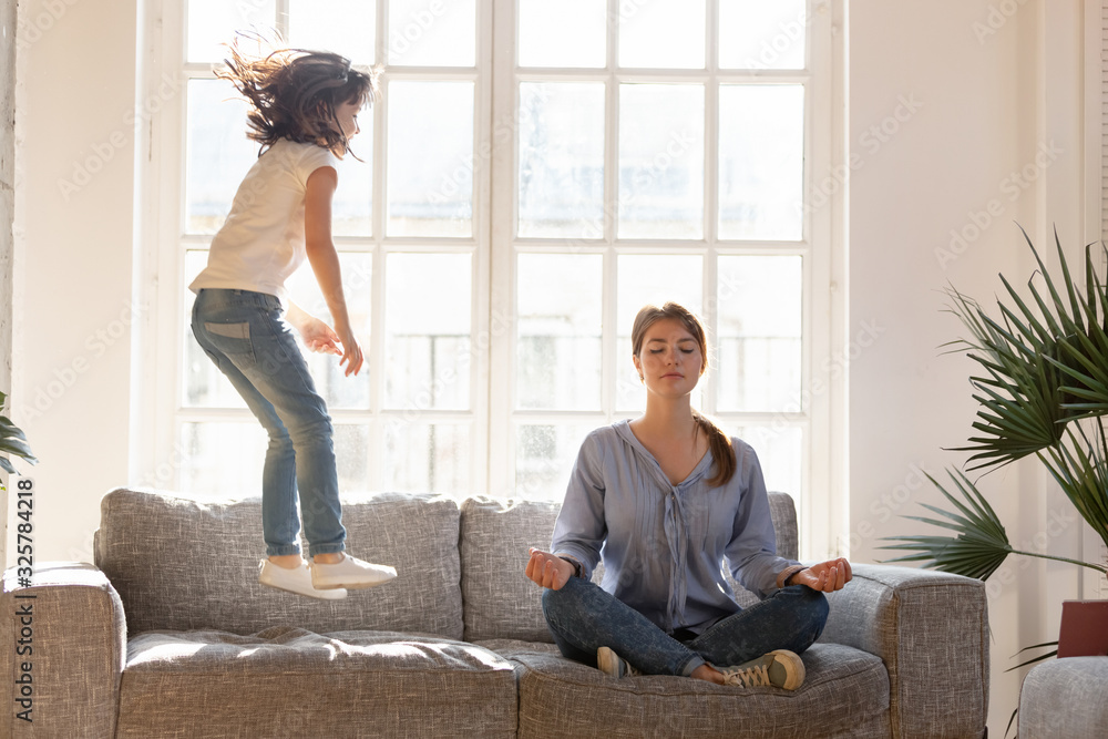 Mom meditating on couch ignore kid jumping near - obrazy, fototapety, plakaty 
