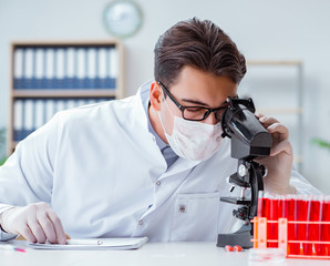 Young doctor working in the lab with microscope