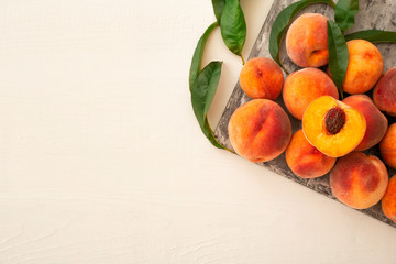 Peaches with leaves on a gray board. Flat lay composition with ripe juicy peaches on a white background with copy space. Harvest of peaches for food or juice. Top view fresh organic fruit, vegan food.