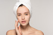 © LIGHTFIELD STUDIOS - beautiful girl with towel on head applying coconut scrub on face, isolated on grey