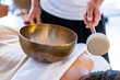 © Valmedia - A masseur standing with a Tibetan bronze sound bowl with a stick. A professional massage therapist giving a sound massage