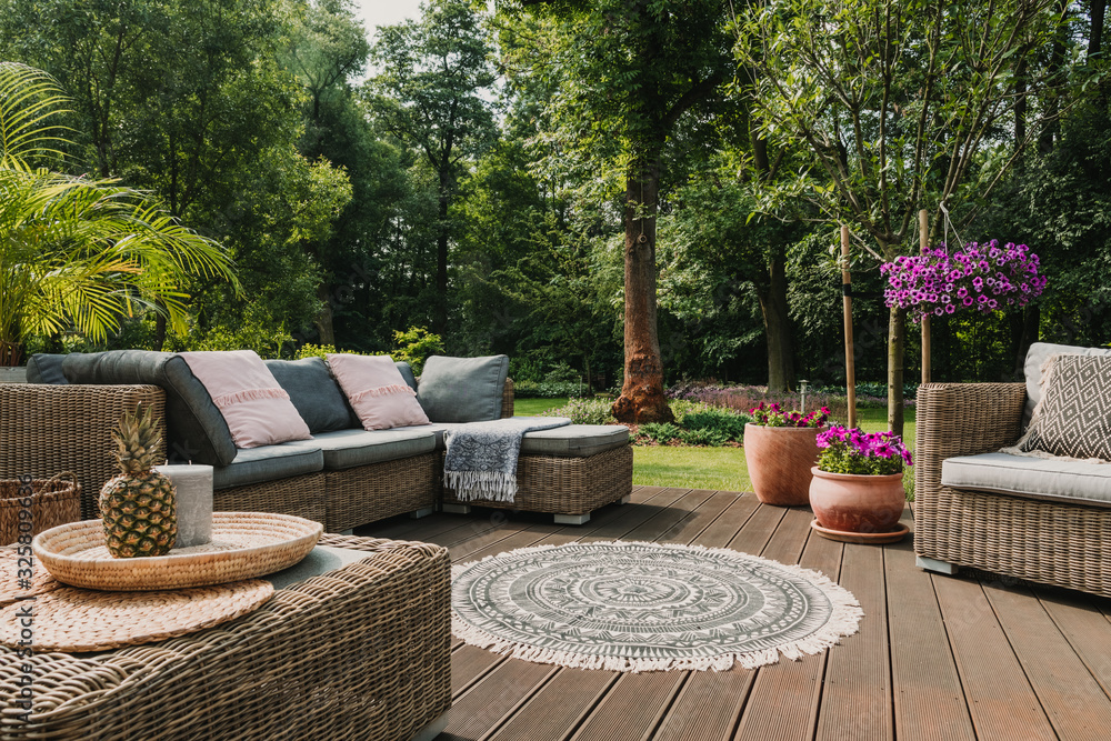 Classy furniture on wooden terrace in green beautiful garden - obrazy, fototapety, plakaty 
