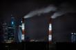 Smoking chimneys over a city at night