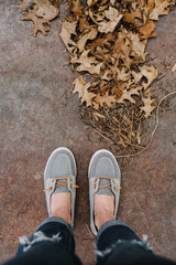 Shoes standing on pavement near autumn leaves