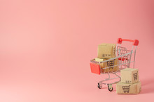 Shopping Concept : Cartons Or Paper Boxes In Red Shopping Cart On Pink Background. Online Shopping Consumers Can Shop From Home And Delivery Service. With Copy Space