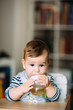 Cute baby boy drinking tea from bottle.