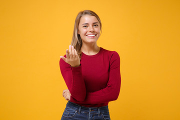 Wall Mural - Smiling young blonde woman girl in casual clothes posing isolated on yellow orange background in studio. People lifestyle concept. Mock up copy space. Doing calling gesture like says come here to me.