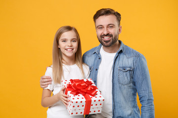 Smiling bearded man have fun with child baby girl. Father little kid daughter isolated on yellow background. Love family day parenthood childhood concept. Hold red present box with gift ribbon bow.