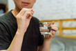 © twinsterphoto - Young Asian man feeling sick and taking pills while sitting on the bed at home with medicines tablets and drinking water on table. Healthcare and Medicine concept