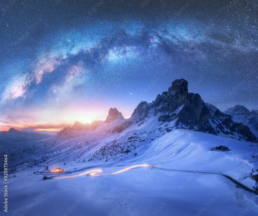 Milky Way over snowy mountains and blurred car headlights on the ...