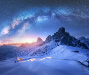 Wall Mural - milky way over snowy mountains and blurred car headlights on the winding road at night in winter. be