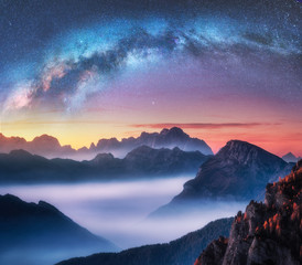 Wall Mural - milky way above mountains in fog at night in summer. landscape with alpine mountain valley, low clou