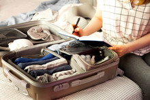Open Grey Suitcase With Different Clothes Packed For Journey At Home. Nordic Style Minimalism. Woman Packing Bags For Holidays And Preparing Things For Vacations Getting Ready For Travel