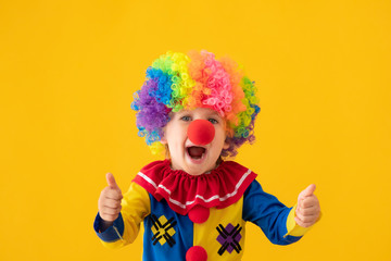 Wall Mural - Funny kid clown playing against yellow background