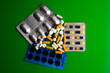 Different tablets, pills, medications drugs on green background