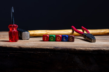 Different tools and the letters tools on a wooden surface