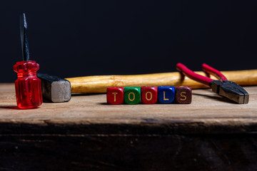 Different tools and the letters tools on a wooden surface